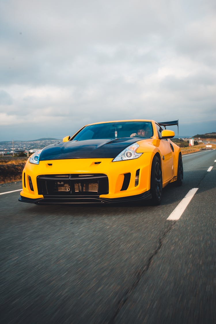 A Man Driving A Nissan Sportscar On The Road