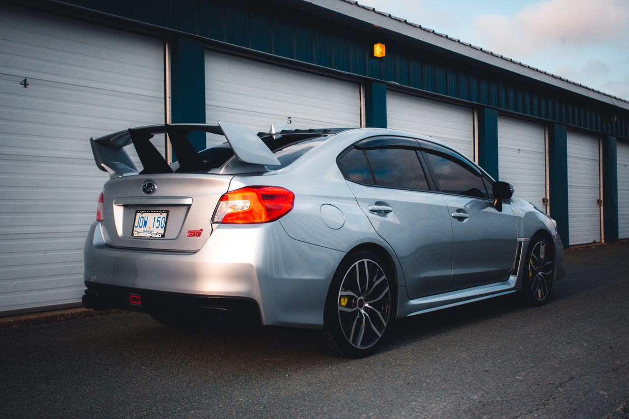 a sleek silver subaru wrx sti parked near industrial garage doors show