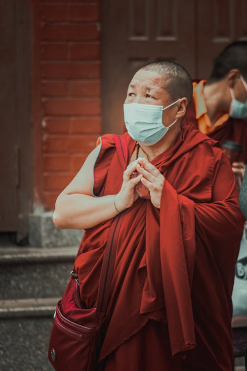 A Monk Wearing Face Mask while Praying