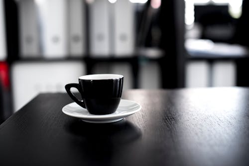 черно белая керамическая чашка чая с блюдцем на черном деревянном столе