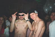 这是一场热闹的夜间活动，人群中，一名赤裸上身的男子纹着身，戴着墨镜