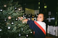 一名妇女在室内用金银饰品装饰圣诞树，增添节日气氛