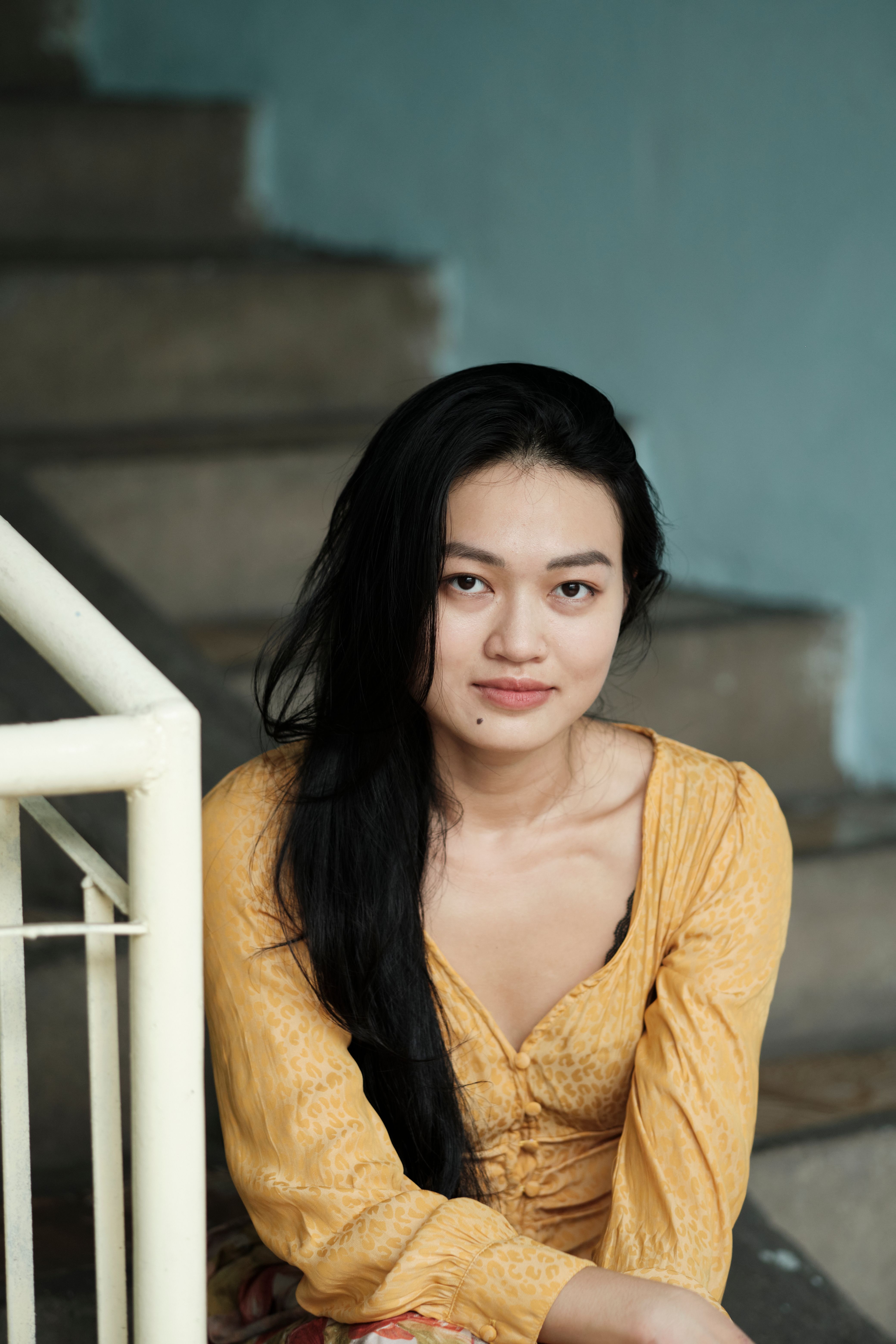 A thoughtful woman sits on steps indoors, capturing a quiet moment.