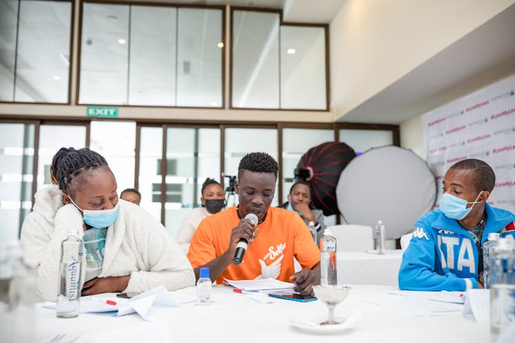 People Sitting By Table Wearing Face Masks