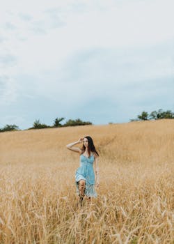 A woman in a blue dress strolls through a wheat field on a clear day in Des Moines, Iowa.