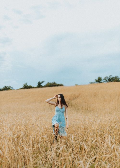 Free A woman in a blue dress strolls through a wheat field on a clear day in Des Moines, Iowa. Stock Photo