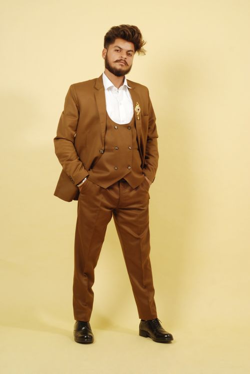 Free Stylish bearded man posing in a classic brown suit in a studio setting with a neutral background. Stock Photo