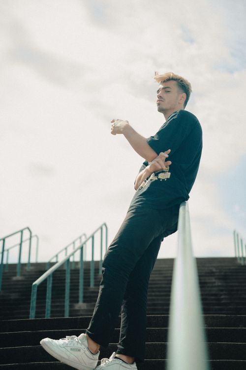 Free Man in a casual pose leaning on a handrail of outdoor stairs on a sunny day. Stock Photo