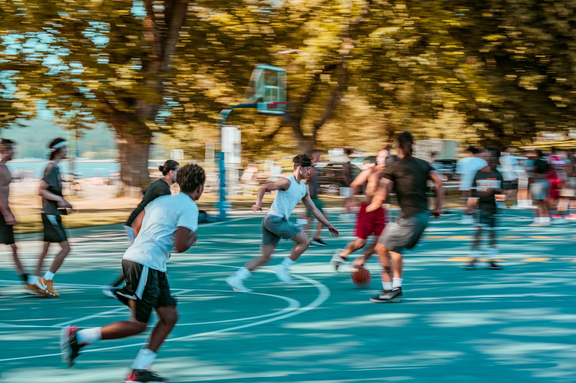 Vibrant street basketball game in a lively park setting with motion blur effect.