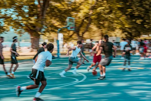 Vibrant street basketball game in a lively park setting with motion blur effect.