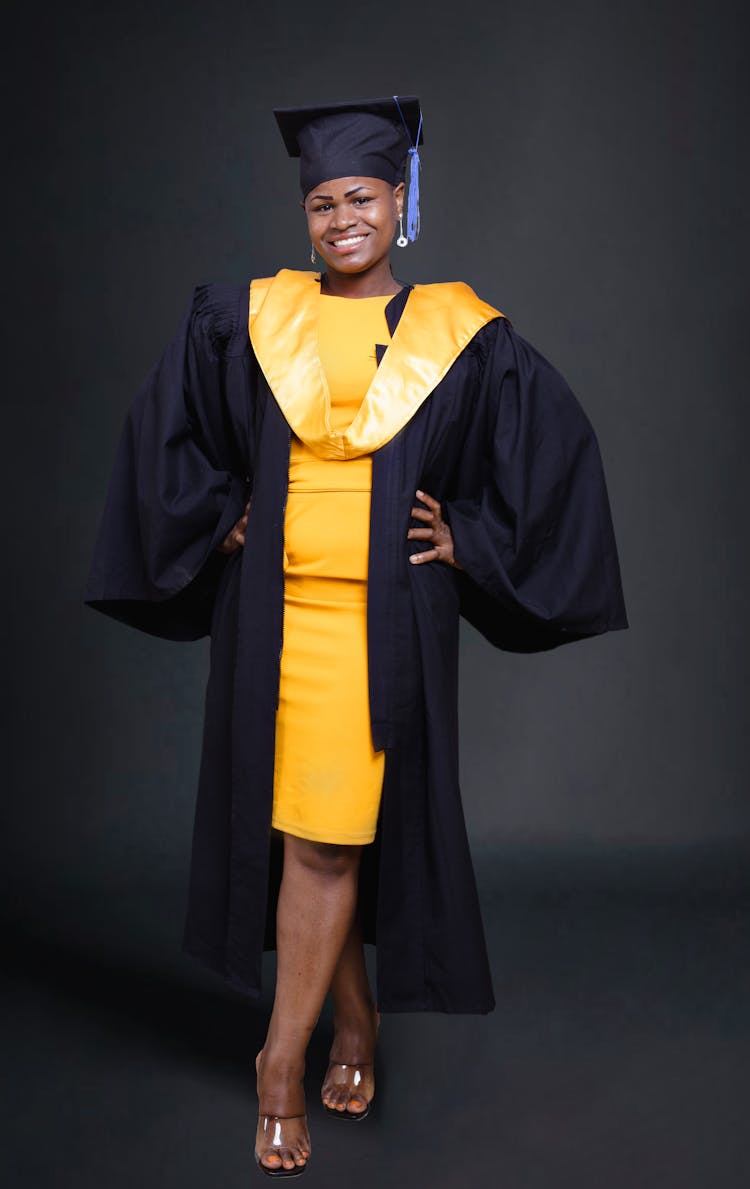 Woman In A Yellow Dress Wearing A Graduation Gown And Stole