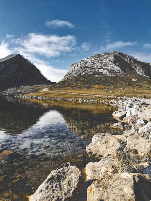 Rocks Near a Lake and Mountains Under a Blue Sky