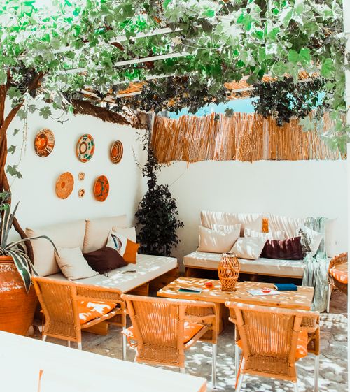 Free Inviting outdoor patio with wooden furniture and rustic wall decor under lush greenery. Stock Photo