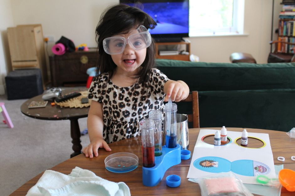 Young girl smiling as she experiments with test tubes in a playful science activity.