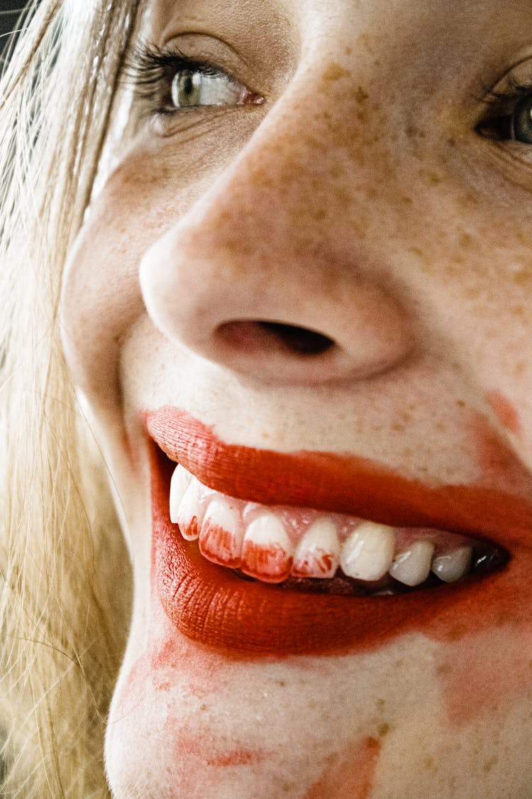 A Woman With Red Lipstick On Teeth