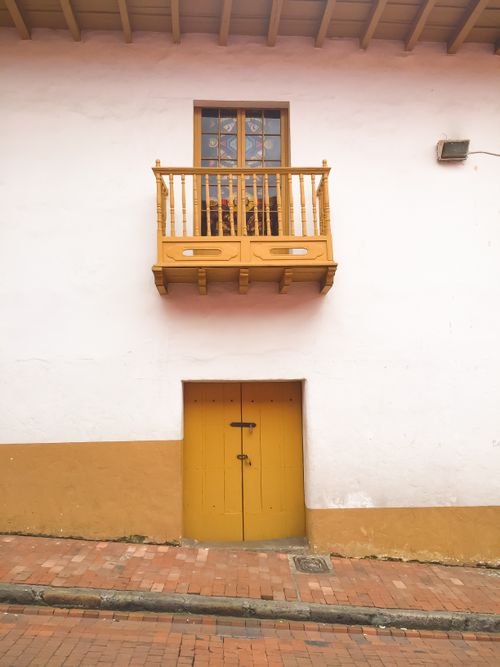 Free Charming colonial facade with yellow balcony and door on a street in Bogotá, Colombia. Stock Photo
