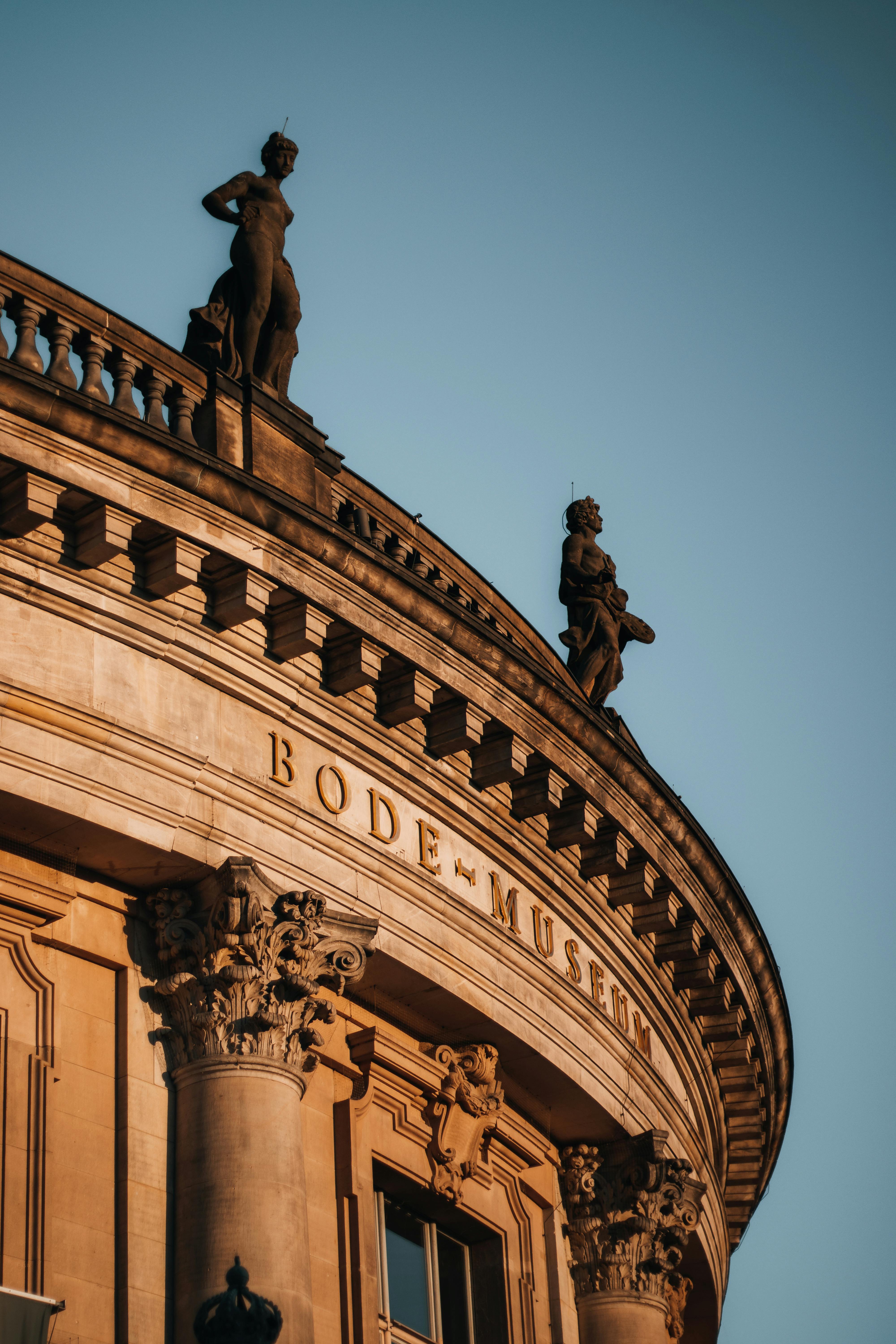 Low-angle view of Bode Museum's exterior with classical sculptures against a clear sky in Berlin.