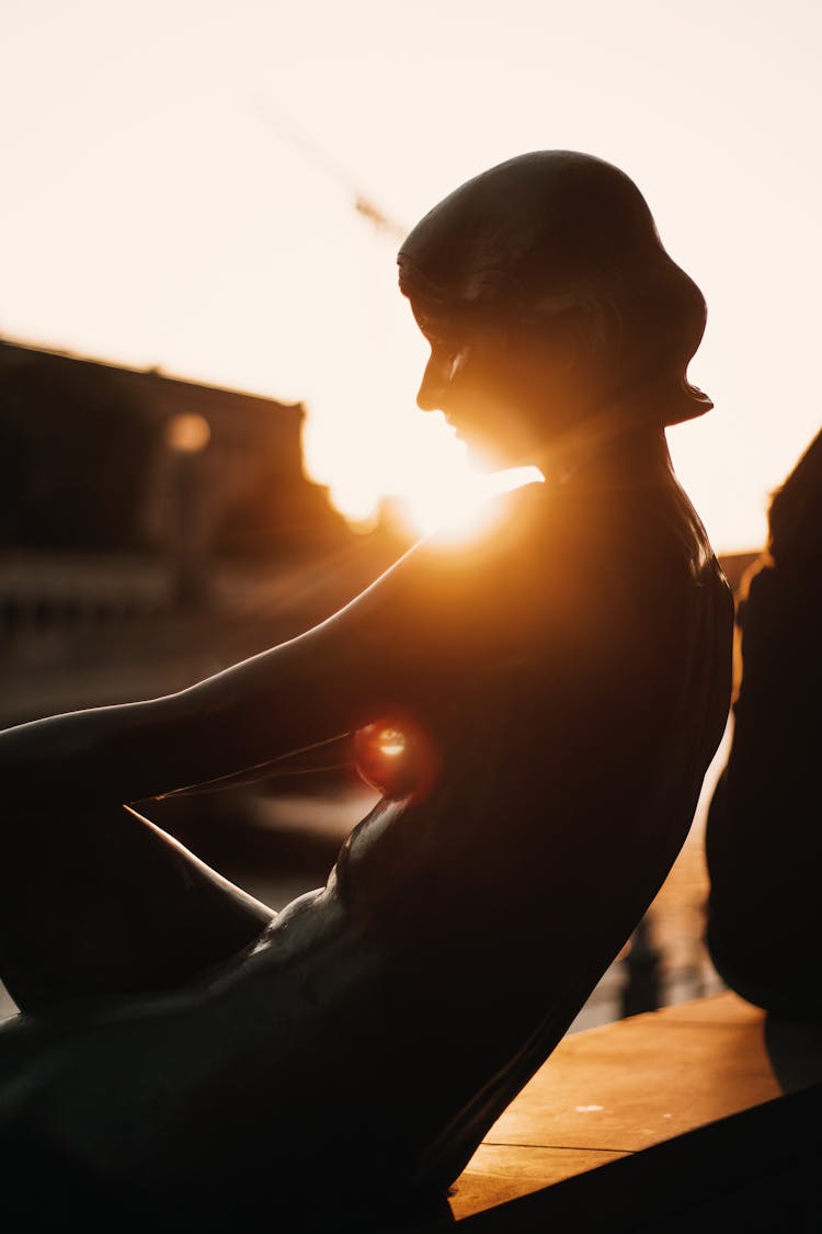 Statue Of Woman Sitting On Concrete Bench