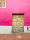 波哥大一栋建筑的外观色彩缤纷，粉红色的墙壁引人注目，木制门则显得质朴