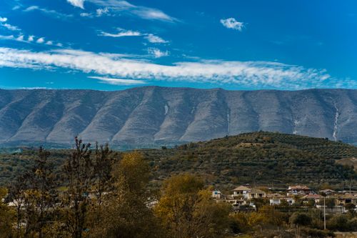 Free Explore a serene village nestled against a stunning mountain backdrop under a clear, blue sky. Stock Photo