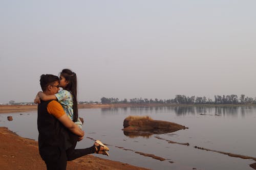 A Girl Hugging and Kissing her Father by a Lake 