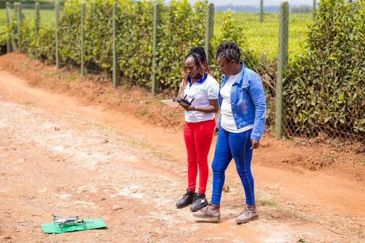 Women Operating Drone On Dirt Road