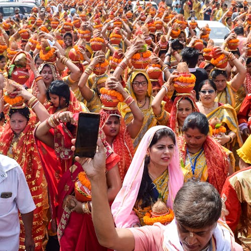 Man Recording Women Holding Kalash over their Heads During March