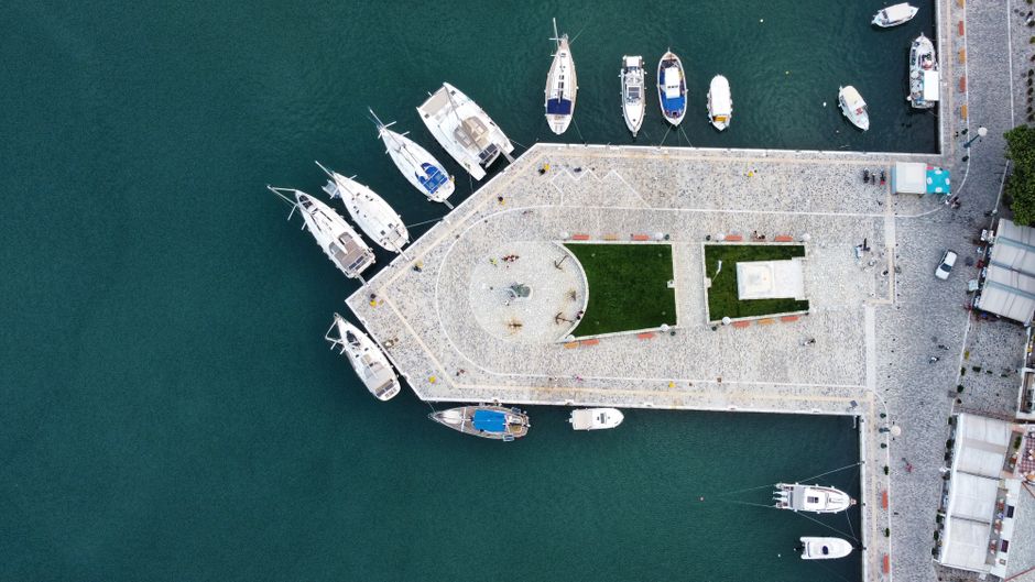 Breathtaking Private Helicopter Transfer from Folegandros to Milos Review 2026 - Aerial drone shot of Skopelos harbor, Greece, showcasing docked boats and a stone pier.