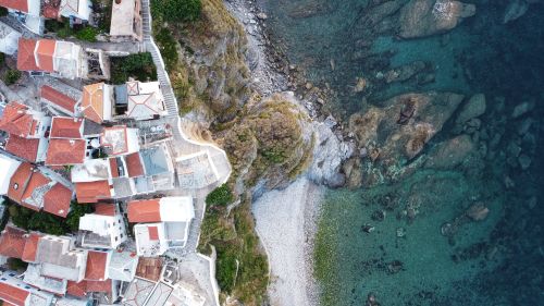 Free Stunning aerial view of Skopelos' coastal village with red-tiled roofs and clear blue waters. Stock Photo