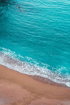 Stunning aerial perspective of a tranquil beach with turquoise waves meeting sandy shore.