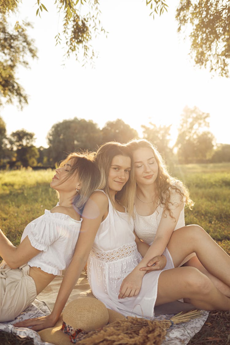 Three Happy Women Sitting On A Blanket In A Natural Setting