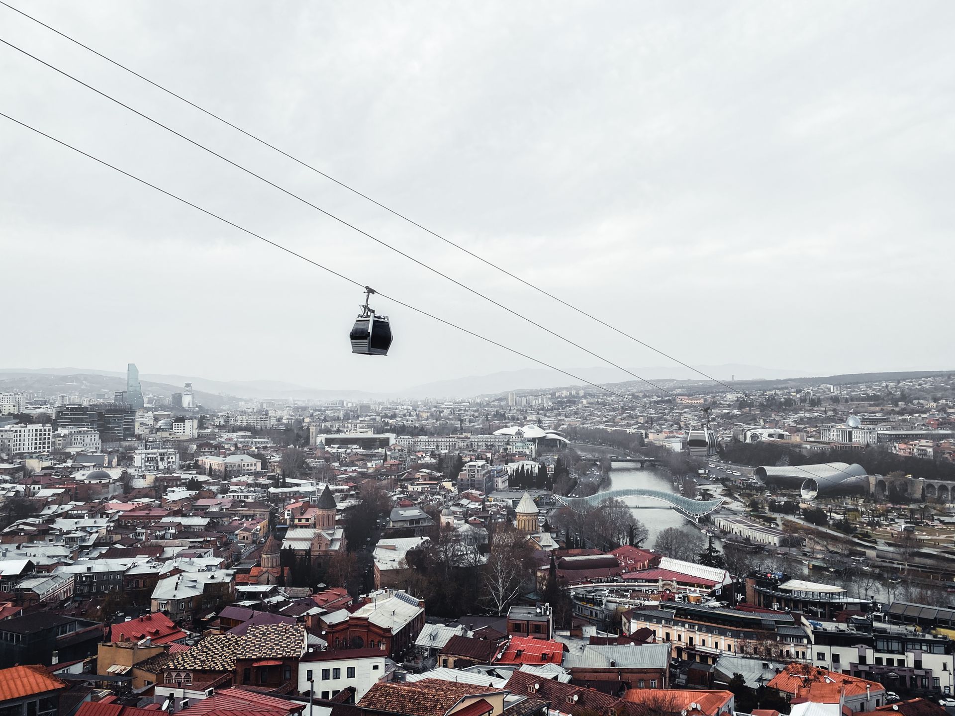 Aerial view of Tbilisi's skyline with a cable car above the urban landscape, showcasing Georgia's architectural blend.
