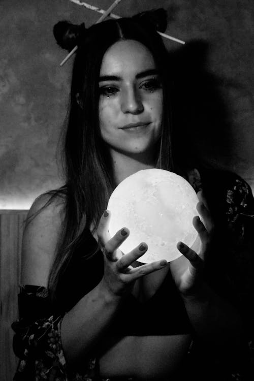 Grayscale Photo of Woman Holding Glass Ball