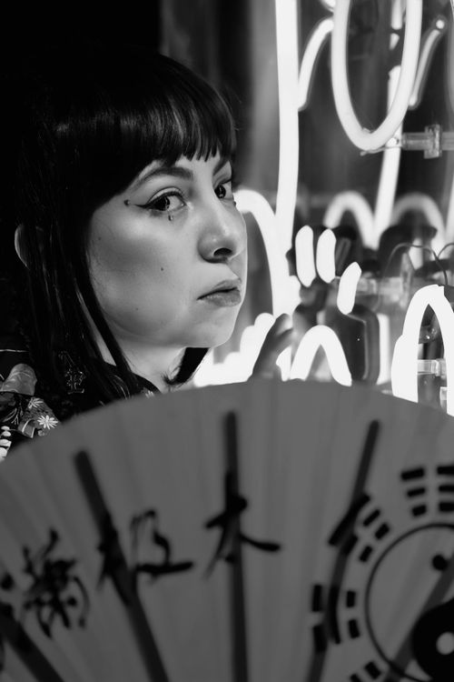 Free Artistic black and white portrait of a woman with neon lights and a folding fan. Stock Photo