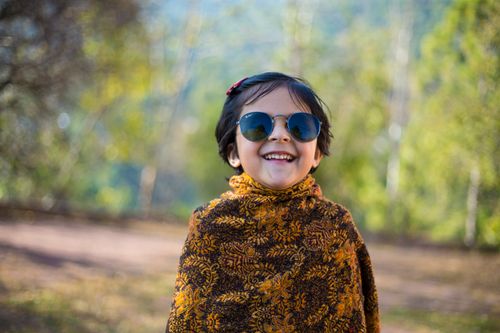 Free Cheerful child wearing sunglasses and shawl outdoors in sunny Murree, Pakistan. Stock Photo