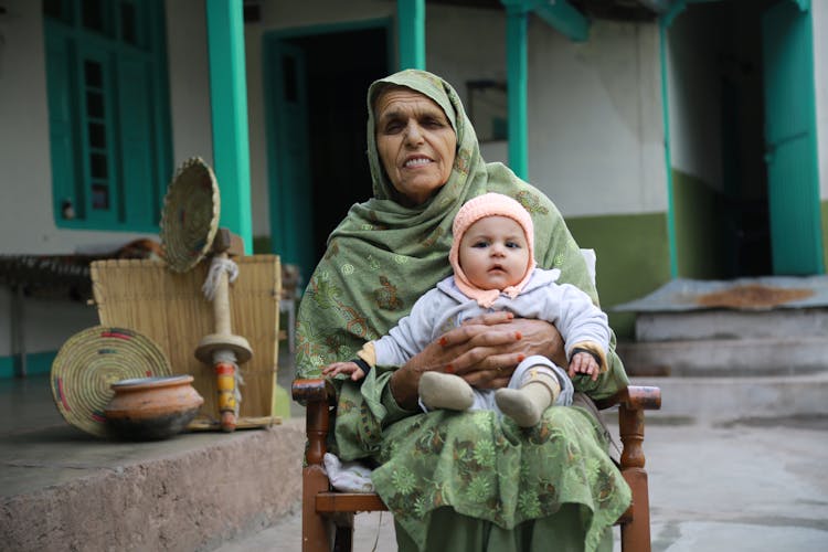 Elderly Woman In Traditional Clothing Sitting With Baby