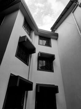 Grayscale exterior photograph of a modern building with windows captured in Xeldem, India.