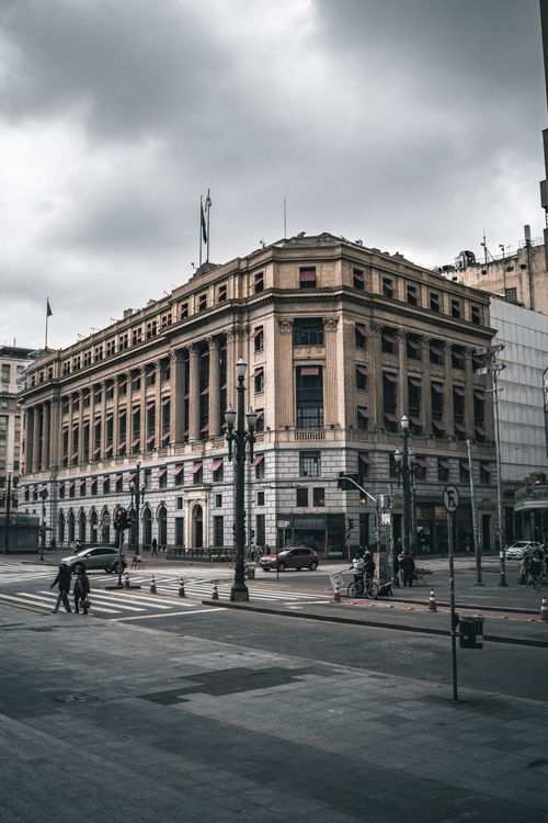 Free A bustling city street scene with a grand historic building and people walking by. Stock Photo