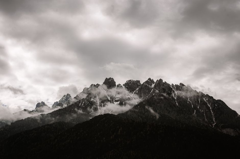 A stunning view of majestic mountains shrouded in clouds, creating a dramatic and moody atmosphere.