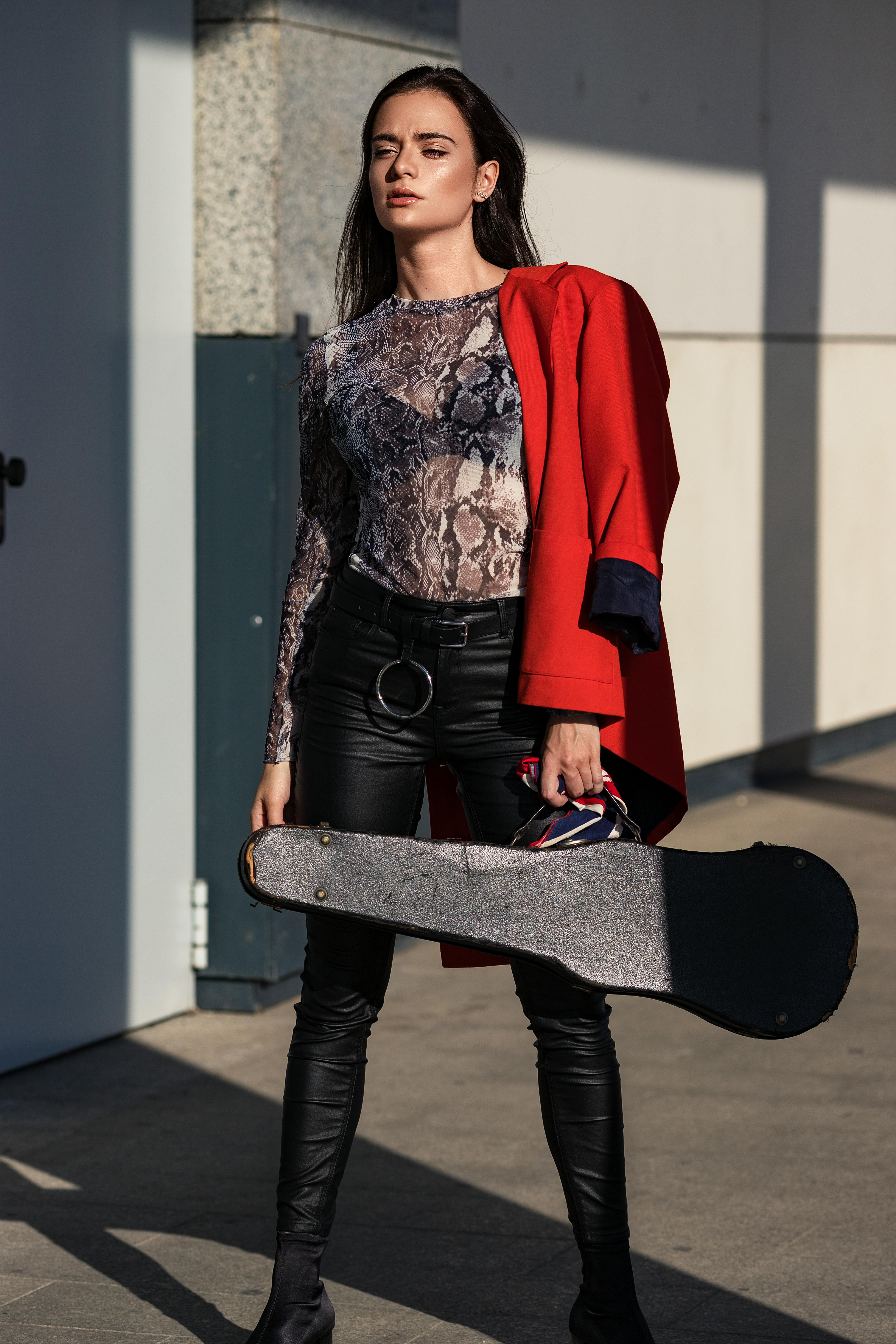 vertical shot of a model posing in red jacket and holding a violin case