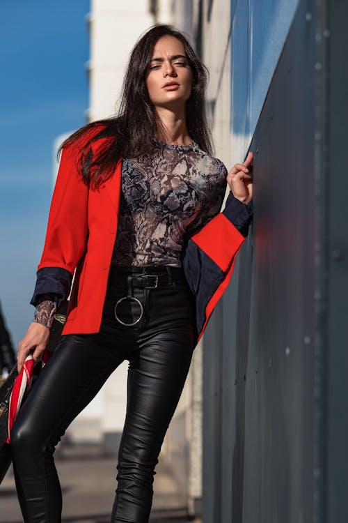 Woman in red leather jacket and black leggings holding white and