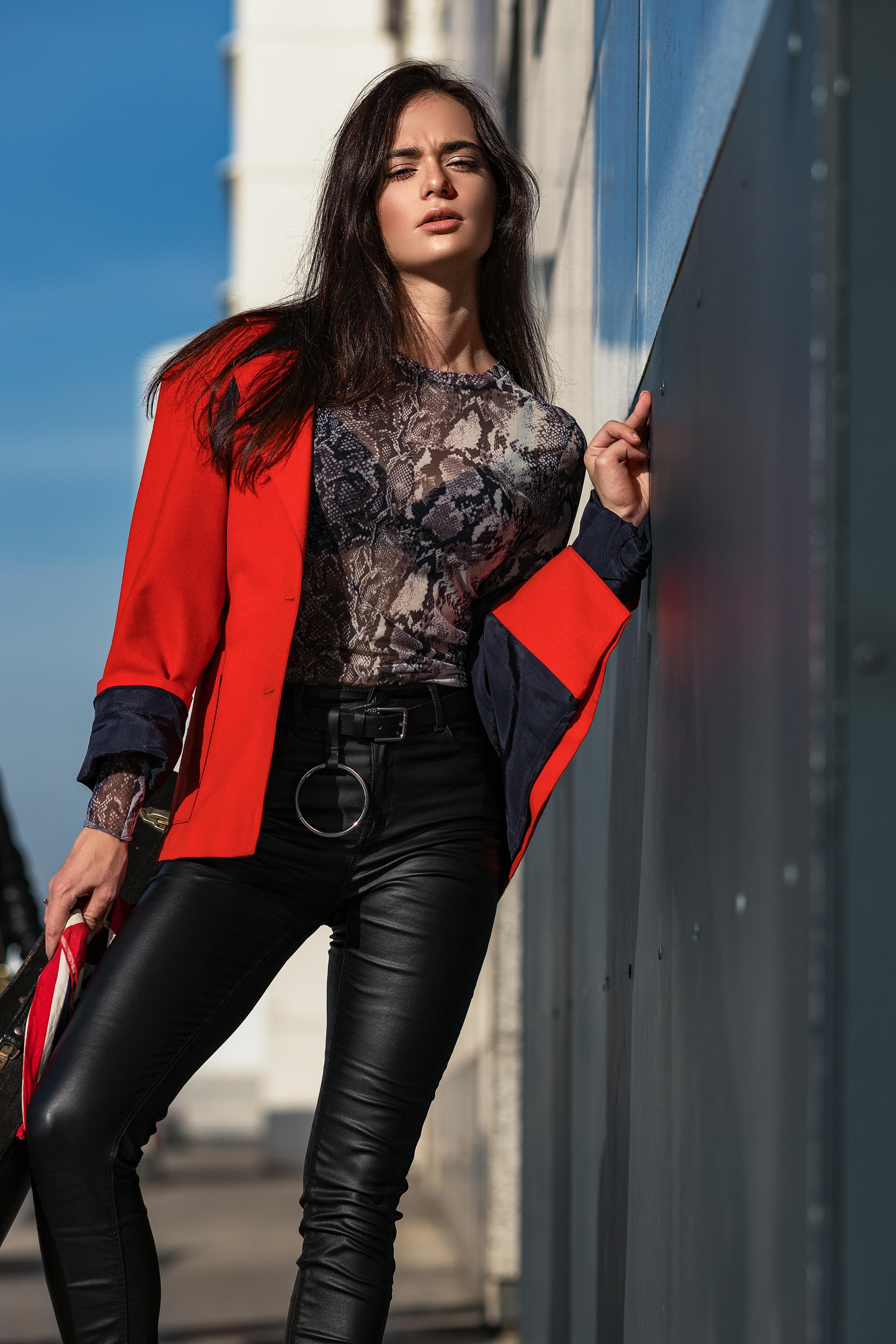 Low Angle View of a Woman in Leather Trousers and Red Leaning against a · Free Stock Photo