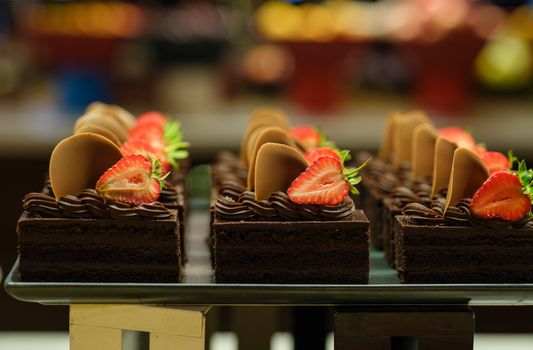 Mouth-watering chocolate cake slices adorned with fresh strawberries and chocolate rounds, perfect for dessert lovers.