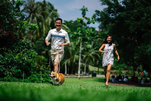 Man and Woman Running Near Green Leaf Trees Photo
