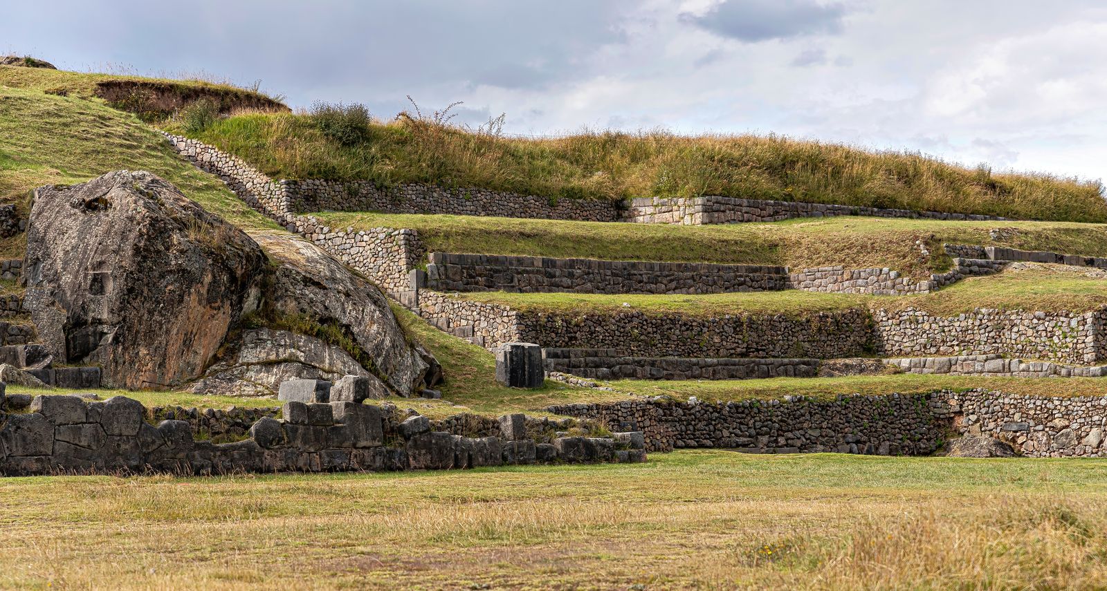 Muros y terrazas de piedra de un sitio arqueológico sobre un cerro de pasto