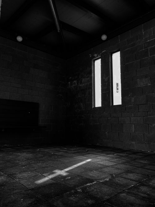 Free Moody black and white shot of an empty abandoned room with a cross-shaped light beam. Stock Photo
