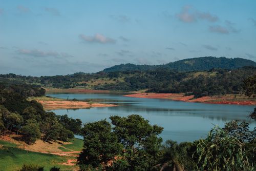 Free A tranquil lake surrounded by lush green hills and a clear blue sky, evoking a sense of peace and natural beauty. Stock Photo