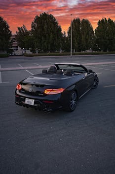 A luxury black convertible Mercedes-Benz parked in Dubai during a vibrant sunset.