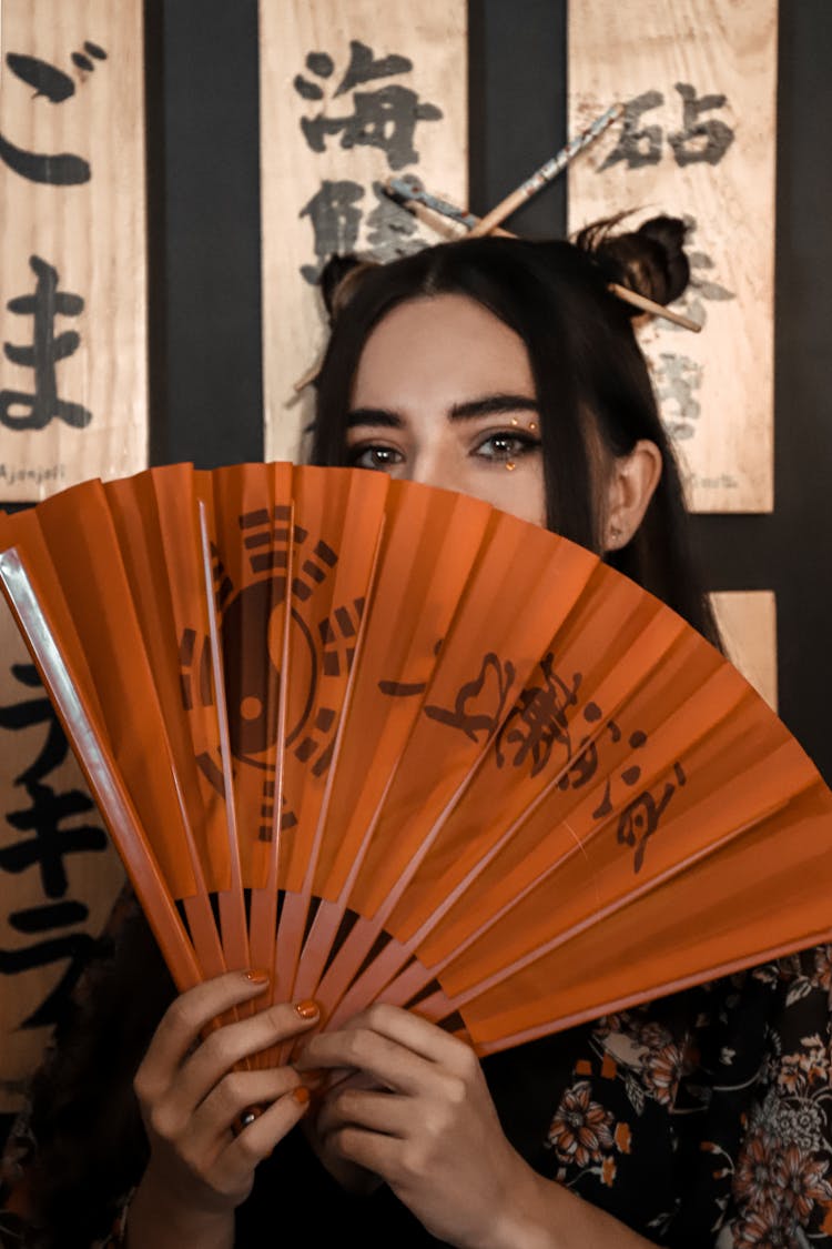 A Woman Covering Her Face With A Fan