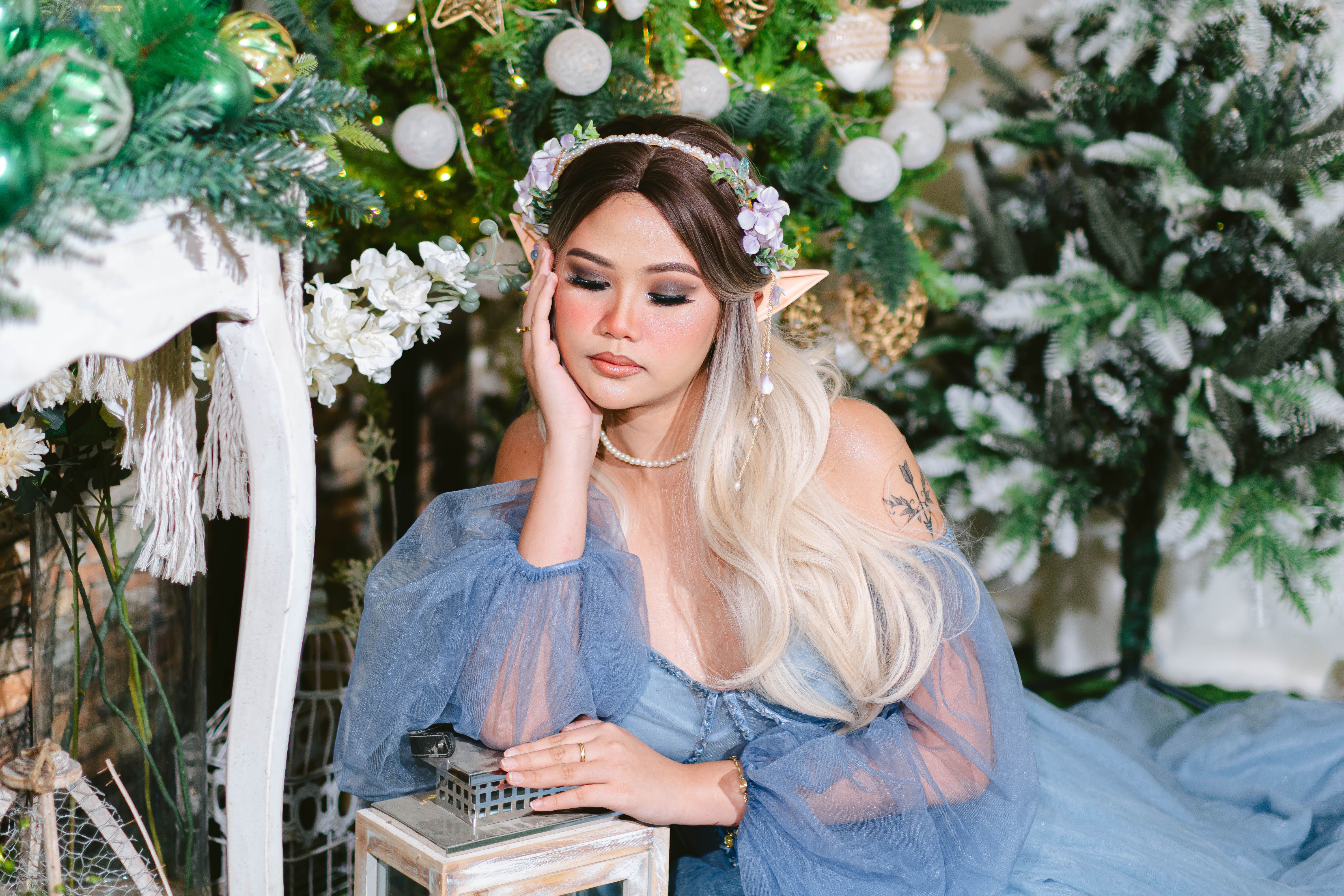 Elegant woman dressed as an elf amid a whimsical forest backdrop, exuding tranquility.